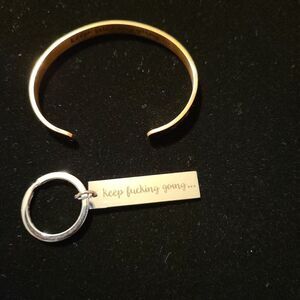 A rose gold cuff bracelet and a silver key chain